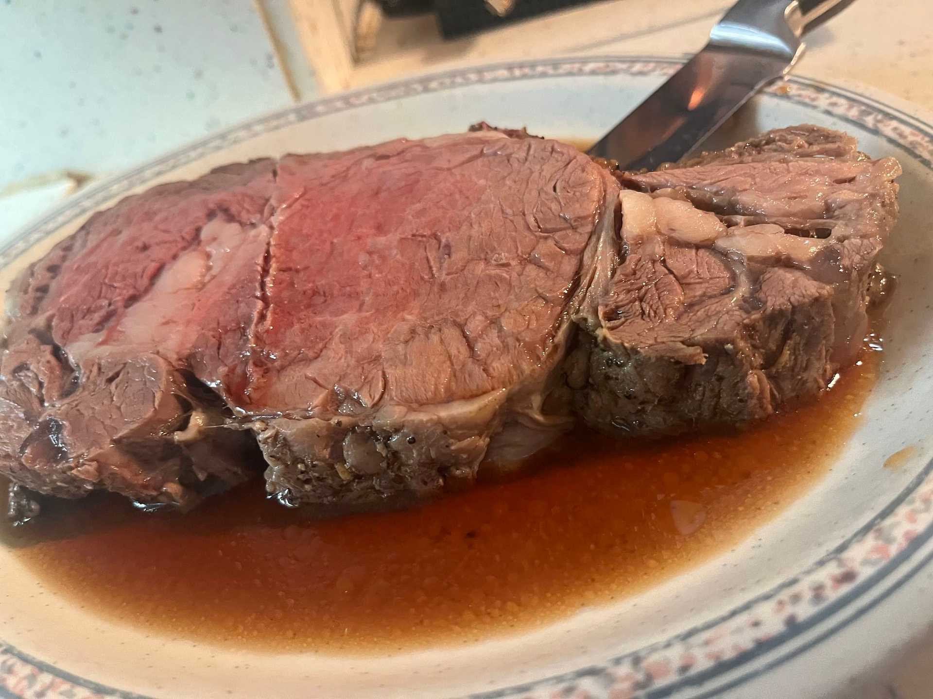 Juicy roast beef slices on a plate with a carving knife in the background.