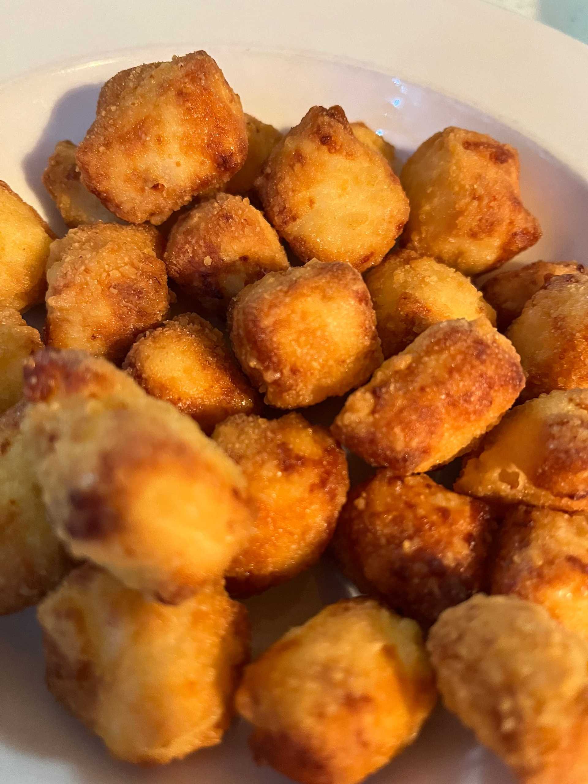 Golden, crispy tater tots piled in a white bowl, ready to be served.